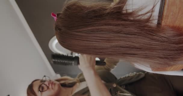 Κομμώτρια Αναλύοντας Μαλλιά Μιας Κοκκινομάλλας Στο Πλαίσιο Της Προετοιμασίας Για — Αρχείο Βίντεο