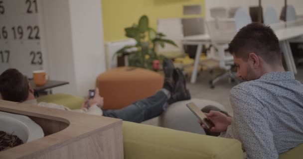 Ofisteki Insanlar Rahat Koltuğa Uzanıp Telefonlarını Modern Ofis Alanlarını Karıştırarak — Stok video