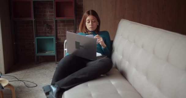 年轻的女人躺在沙发上 在自助餐厅里的笔记本电脑上工作 茶色的 橙色的 卡车的运动 — 图库视频影像