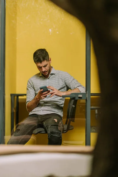 オフィスで防音電話のブートに座っている間 いい男のビジネス人は電話を待っています — ストック写真