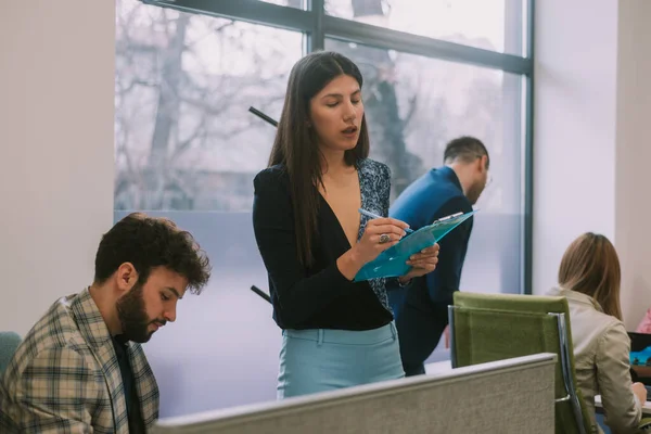 オフィスの机の近くに立っている間にメモを書いている美しいビジネス女性 — ストック写真