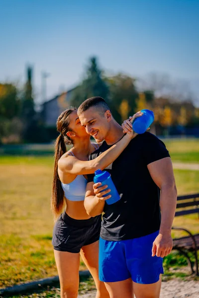A lovely happy sports girl kissing her boyfriend on the cheek. He is happy and smiling
