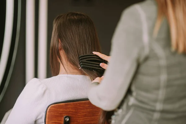 一位金发美发师站在美发厅给客人刷棕色头发 — 图库照片
