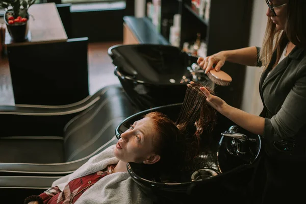 理发师在美发店的洗头槽上刷着客户湿透的头发 — 图库照片