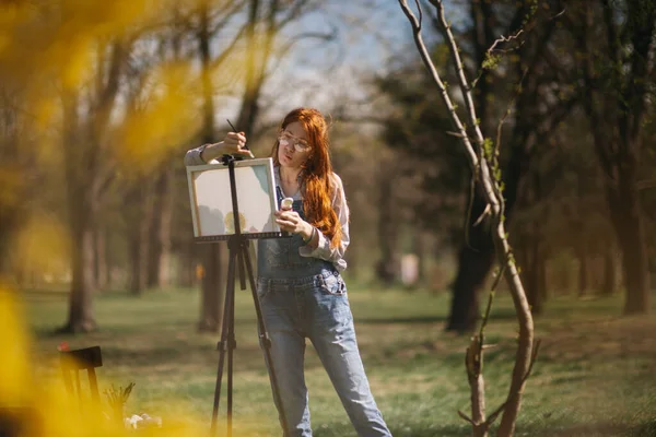 Красивая Девушка Красными Волосами Рисующая Мольберте Стоя Парке — стоковое фото
