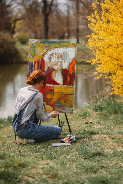 Zbliżenie Imbir Dziewczyna Malowanie Dużym Płótnie Kolorowe Zdjęcie Siedząc Pobliżu — Zdjęcie stockowe