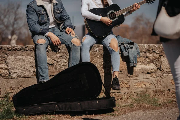 女の子がギターを弾いている公園に座っているカップルの終わり — ストック写真