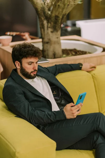Hombre Negocios Bien Parecido Revisando Teléfono Mientras Está Sentado Sofá — Foto de Stock