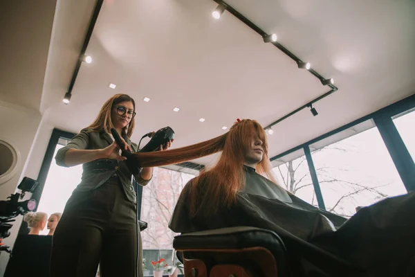 理发师站在理发店里吹着吹干顾客的头发 — 图库照片