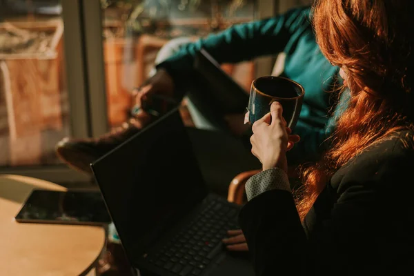 膝の上で作業しながら彼女のお茶の一口を取るために約赤毛の実業家のクローズアップショット — ストック写真