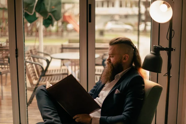 Handsome Bearded Man Writing Something His Notepad His Legs Crossed — Stock Photo, Image