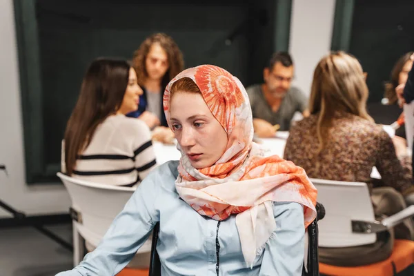 全神贯注的残疾女雇员头戴头巾 在膝上型计算机上工作 完成日常工作任务 坐在轮椅上 头戴头巾 头戴头巾的穆斯林红头发女孩 — 图库照片