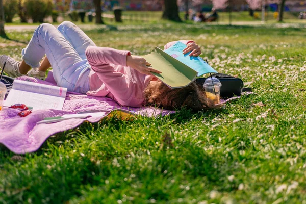 Кудрявая Девушка Закрывает Лицо Книгой Лежа Одеяле Парке Защищает Свое — стоковое фото
