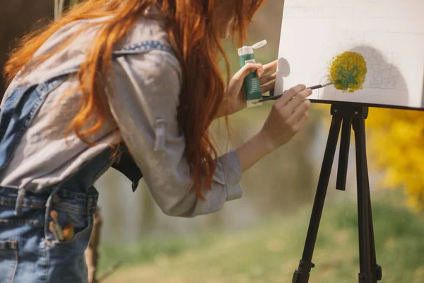 公園に立っている間 緑の塗料でキャンバス上の赤い長い髪の絵を持つ女性の閉鎖 — ストック写真