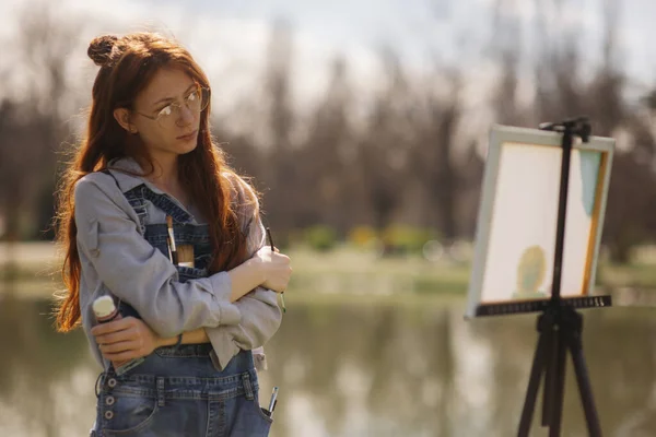Kızıl Uzun Saçlı Bir Kadının Parkta Dikilirken Yaptığı Resme Bakıp — Stok fotoğraf