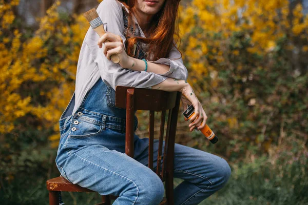 公園に座っている間にオレンジペイントチューブと大きなブラシを保持している生姜の女の子の画家のクローズアップ — ストック写真