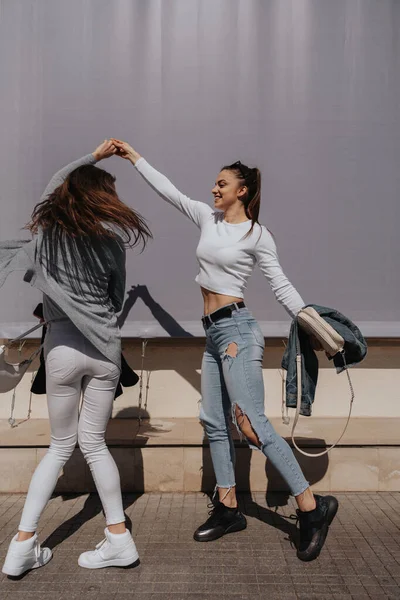 Duas Meninas Morenas Bonitas Dançando Juntas Frente Parede Cinza — Fotografia de Stock