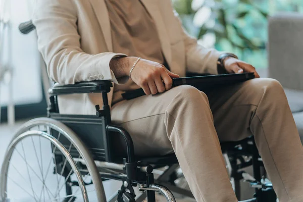 Disabled man on wheelchair in office wearing presentable suit. Adaptation of people with disabilities in society. Recovery and healthcare concept