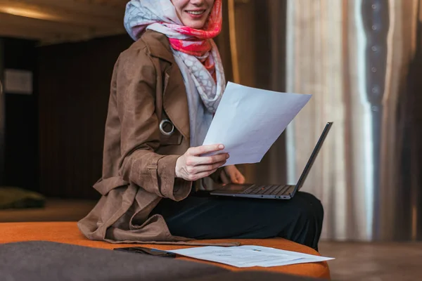 穆斯林妇女头戴头巾 一边看报告一边笑着在笔记本电脑上证明销售数字 — 图库照片