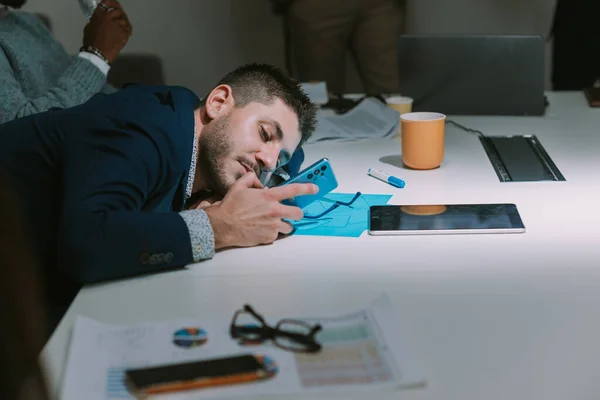 Close Homem Negócios Cansado Olhando Para Telefone Enquanto Deitado Mesa — Fotografia de Stock