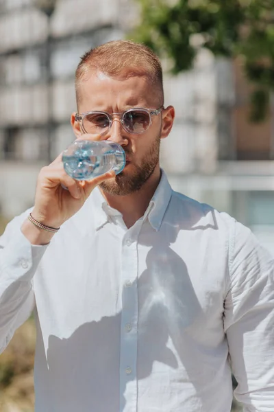 炎热的夏天 一个英俊 金发碧眼的商人在户外远程工作时喝水 — 图库照片