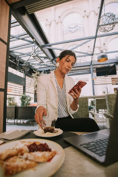 Beautiful business woman looking at the phone while sitting at the cafe