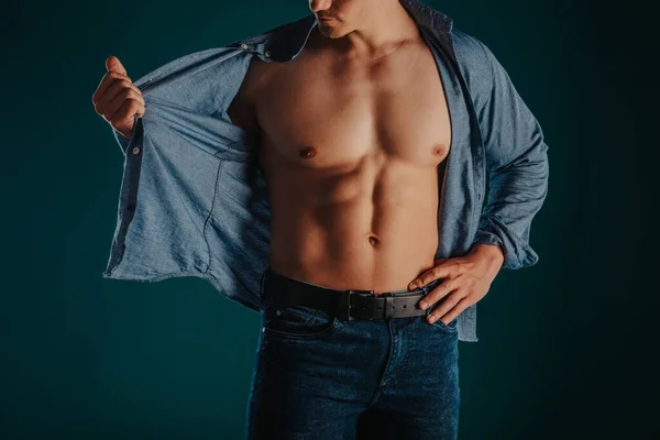 Well-built and stunning man standing in a green room and posing