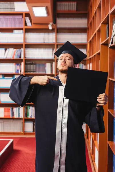 Kendinden Emin Genç Bir Erkek Gururla Üniversite Diplomasını Kütüphanede Tutuyor — Stok fotoğraf
