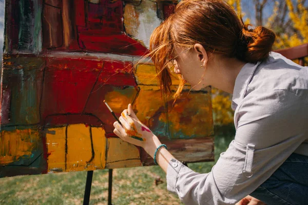 赤い髪の女の子と公園でカラフルな絵を描く束の近くに — ストック写真