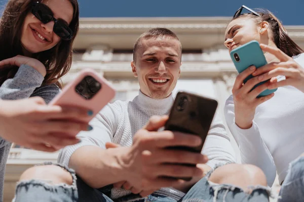 3人の親友を笑顔で閉じ 外で自分の携帯を見ている — ストック写真
