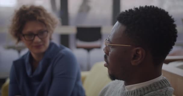年轻的黑人男女和年长的白人女士一边在舒适的办公室沙发上 一边讨论项目细节 一边开车 — 图库视频影像