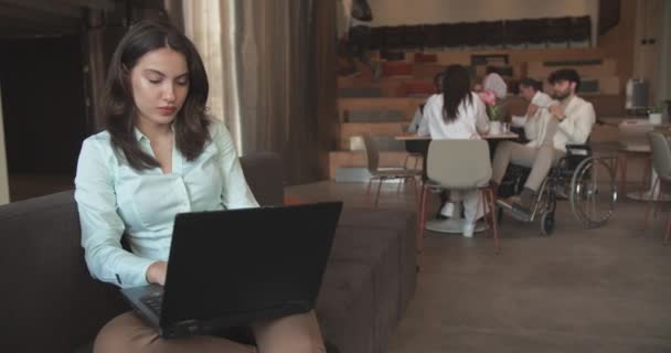 漂亮的年轻女性躺在沙发上 在笔记本电脑上工作 同事们在办公室的咖啡吧里讨论她的商业理念 开卡车 — 图库视频影像