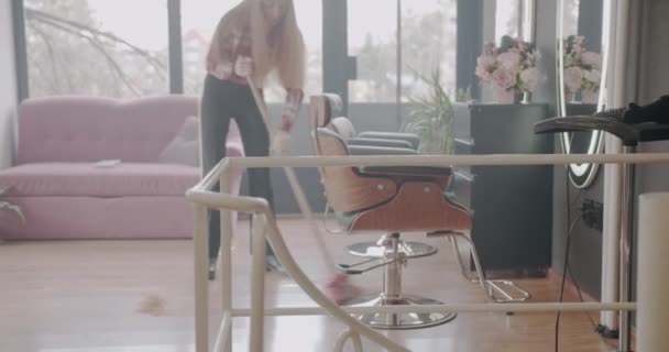 Ξανθιά Κοπέλα Σφουγγαρίζει Πάτωμα Του Στούντιο Hairstyling Μετά Κούρεμα Φορτηγά — Αρχείο Βίντεο