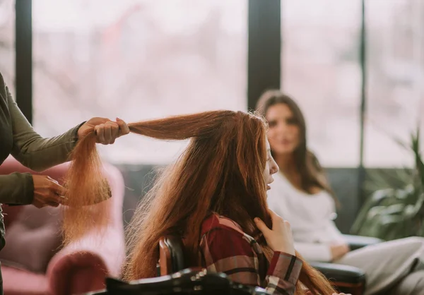 彼女がヘアサロンに座っている間 彼女の顧客に赤い髪をブラッシングヘアスタイリスト — ストック写真