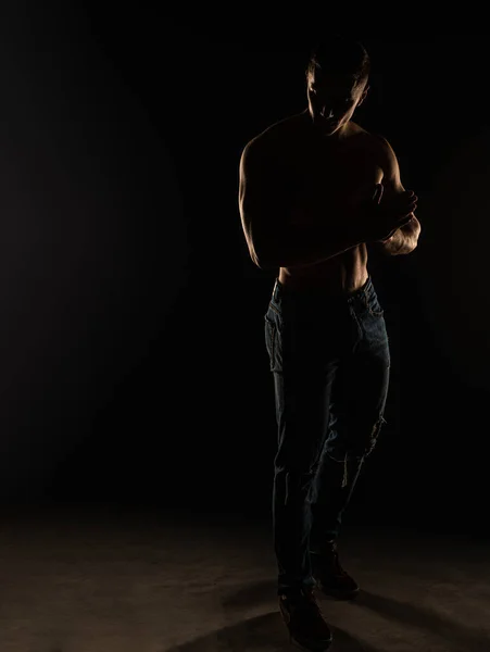 魅力的でハンサムな男は立って彼の姿勢を保持しながらスタジオでトップレスをポーズしています シルエット — ストック写真
