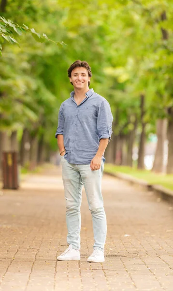 Portrait of young and well-dressed man standing outside and smiling in the sunlight