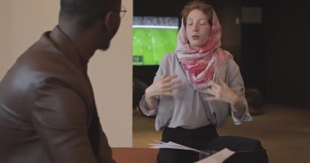 Мусульманская Рыжая Зеленоглазый Девушка Разговаривает Своим Черным Коллегой Офисе — стоковое видео
