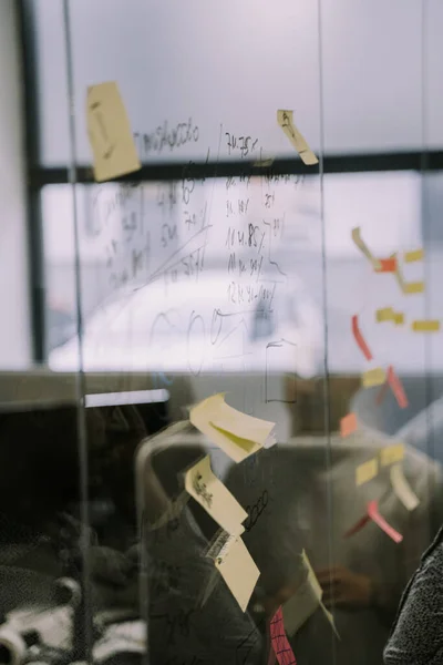 在现代办公室的玻璃墙上写着一些生硬的笔记 想法和计算 — 图库照片
