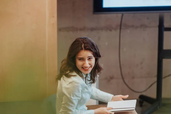 Beautiful brunette female employee smiling while having fun conversation with colleague during break at work