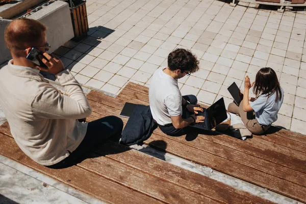 People sitting on bench in the city working remotely using digital devices