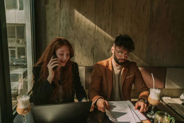 可爱的红头发女商人在打电话 而她的男性商业伙伴在看文件 — 图库照片