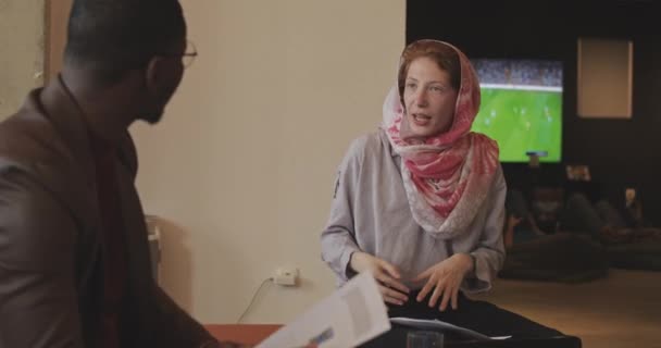在办公室里和她的黑人同事说话的穆斯林绿眼睛姑娘 — 图库视频影像