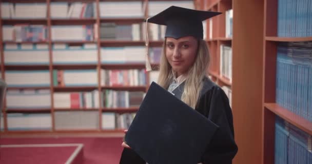 卒業証書が大学を卒業した後 誇らしげに図書館で卒業証書を保持していることを示す学生 — ストック動画