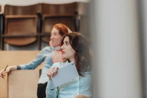 Lovely business girl looking and listening to her coworker discussing new business idea. Business girl holding notebook and looking aside at her colleague