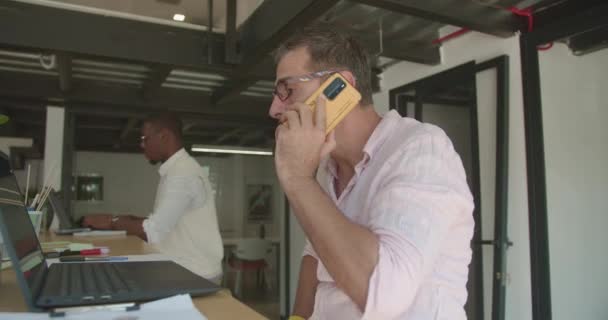 Hombre Mayor Hablando Por Teléfono Mientras Sus Colegas Están Trabajando — Vídeos de Stock