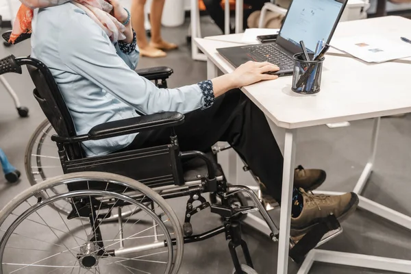 坐在轮椅上的残疾员工在膝头工作 — 图库照片