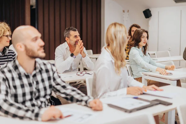 一群商人聚集在一个白色教室的研讨会上 参加一个会议 — 图库照片