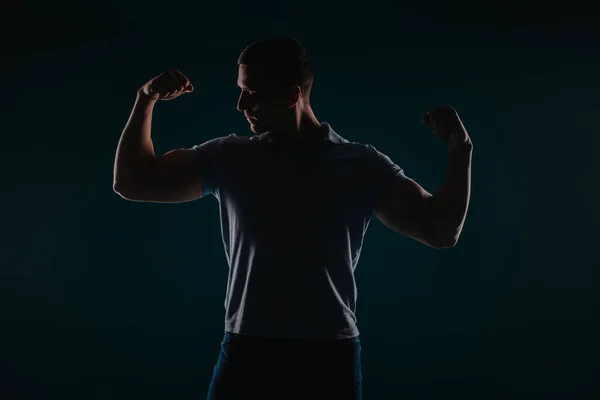 Atrakcyjny Dobrze Zbudowany Mężczyzna Stojący Ciemnym Pokoju Napinający Bicepsy — Zdjęcie stockowe