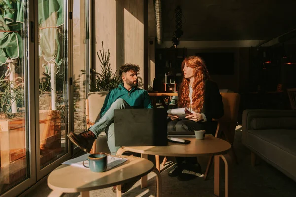 若いビジネスパートナーは 美しい晴れた朝にコーヒーバーで遠隔で働いています 彼らはビジネスを議論しています — ストック写真