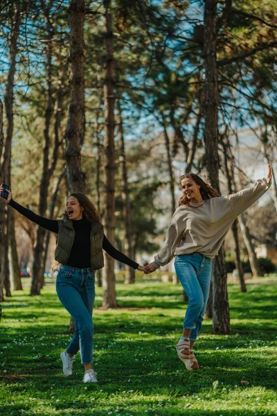Parkta Yürürken Zıplayan Şarkı Söyleyen Iki Mutlu Kız Güneşli Bir — Stok fotoğraf